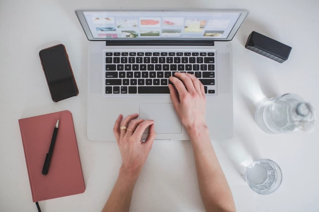 Poste de travail vu du dessus : ordinateur portable, carnet et téléphone