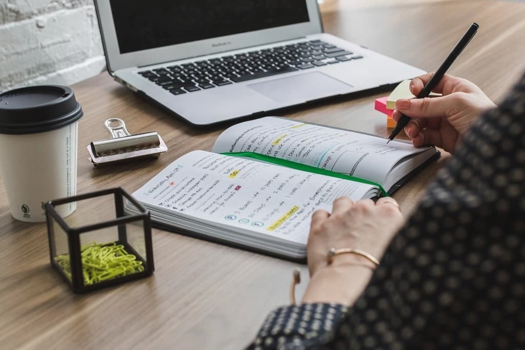 Annotation d’un document au surligneur, à côté d’un ordinateur portable
